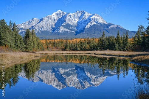 Majestic snow-capped mountains reflect in a tranquil lake surrounded by vibrant autumn foliage