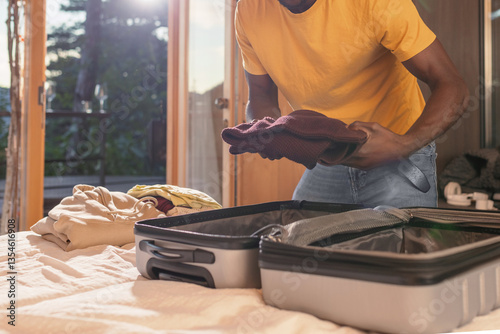 On checkout day, an African American man packing and zipping his suitcase, ready to leave a hotel room. Travel, and departure concepts.
