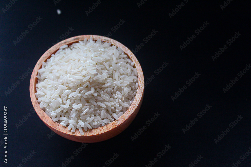 Zakat fitrah concept: Wooden bowl filled with rice on a black background. Zakat fitrah concept: Wooden bowl filled with rice on a black background.