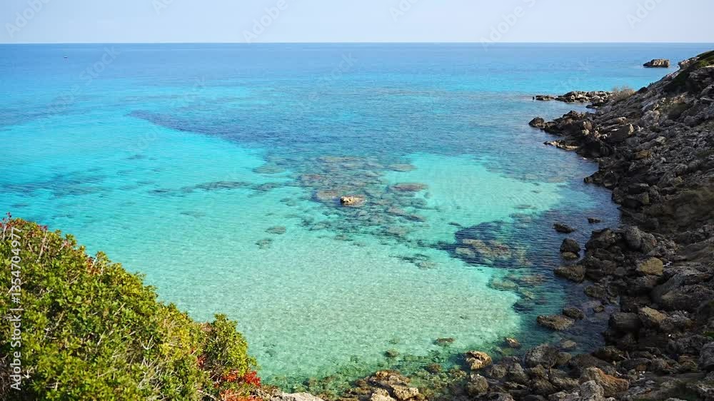 Coastline with a sandy beach and rocky shores near the northeasternmost cape of Northern Cyprus. Crystal-clear waters of a blue lagoon and the untouched beauty of the Mediterranean Coastline with a sandy beach and rocky shores near the northeasternmost cape of Northern Cyprus. Crystal-clear waters of a blue lagoon and the untouched beauty of the Mediterranean