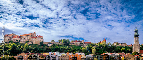Panoramabild der Stadt Burghausen an der Salzach mit Burganlage unter weiß-blauem Himmel 