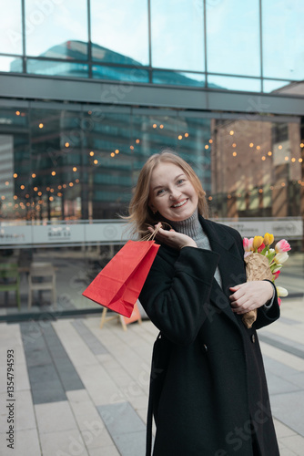 Obraz na płótnie Happy young lady with shopping bag holding a bouquet of yellow tulips, for spring holiday celebrating mother's day or women's day. Woman's Day sale, discount or promotion concept. w salonie