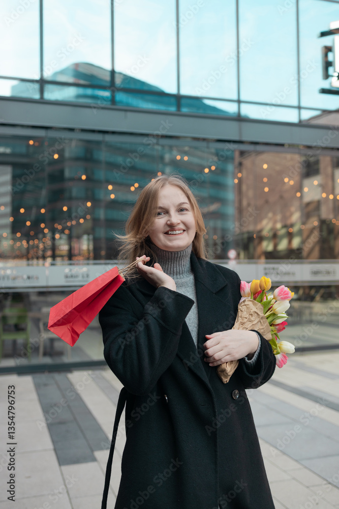 Happy young lady with shopping bag holding a bouquet of yellow tulips, for spring holiday celebrating mother's day or women's day. Woman's Day sale, discount or promotion concept.