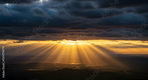Golden Sun Rays Shining Through Dark Clouds Over Mountainous Landscape