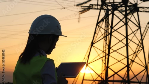 silhouette electrician engineer hand holding tablet. electric power industry high voltage. employee electrician works sunset. energy concept. electric tower high voltage. power line. work tablet sun.