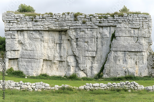 Ancient stone wall, weathered texture, archaeological site, historical landmark,  ruins,  grassy foreground.