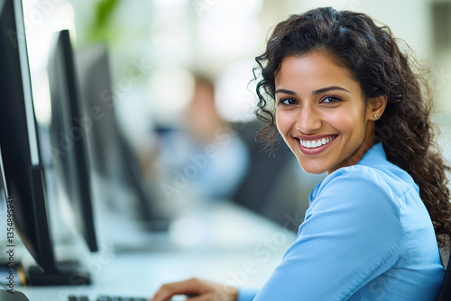Smiling woman with curly hair working at a desk with computer in bright modern office. Looking at camera with joyful expression. Free Download Smiling woman with curly hair working at a desk with computer in bright modern office. Looking at camera with joyful expression. - GFXLoad