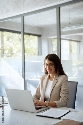 Professional it specialist latin hispanic business lady working on laptop pc sitting at desk in modern office space. Middle eastern indian woman using computer technology app for work online. Vertical