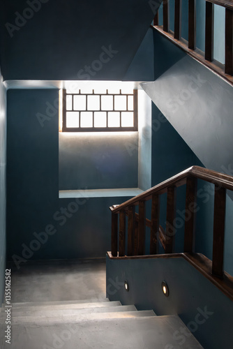Blue-painted staircase with wooden banisters and dazzling light through the window