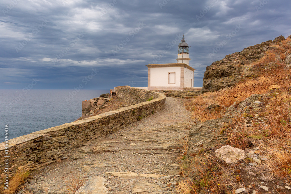 Coastal view of Far de Cala Nans lighthouse near Cadaques in Catalonia, Spain under cloudy skies