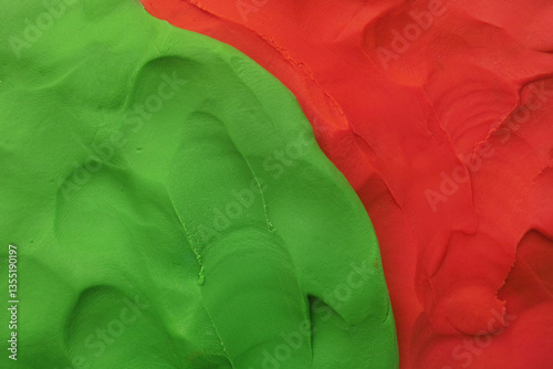 A background texture made out of green and red play clay. Close up.