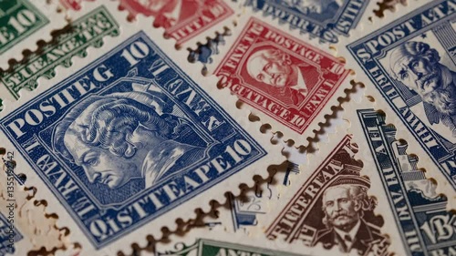 Close-up video of vintage postage stamps in various colors and designs, captured from a top-down angle, highlighting intricate details.