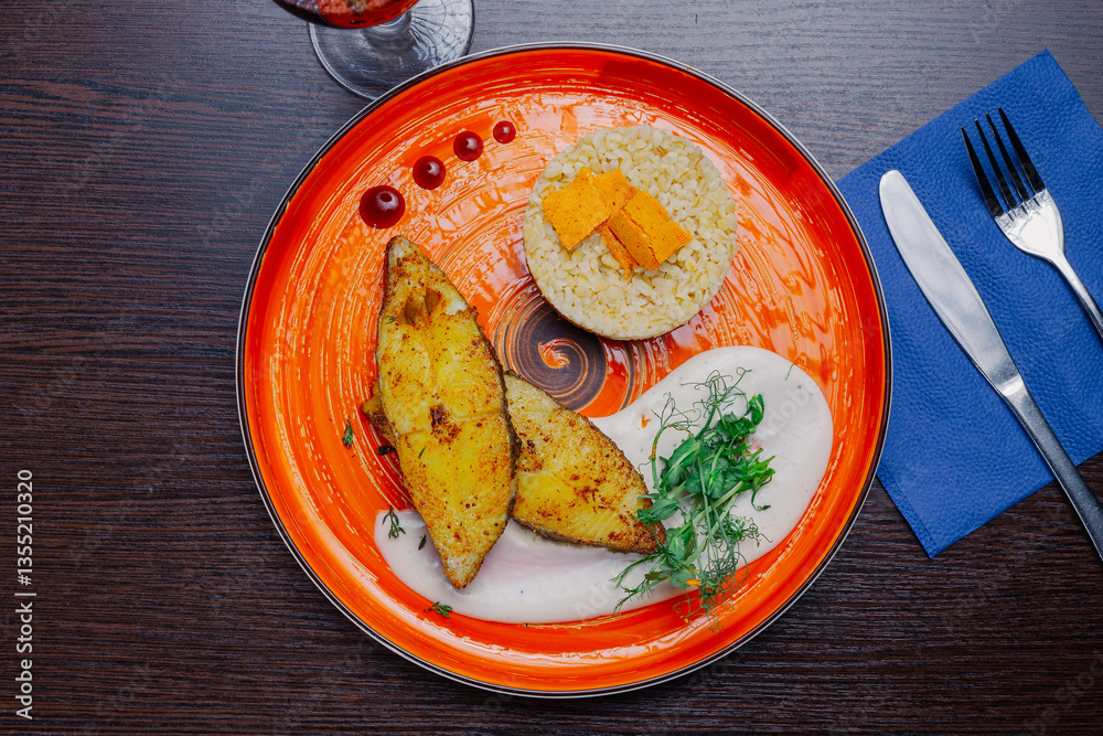 Grilled fresh red fish lies on a plate along with a side dish and sauce. delicious fresh wholesome food in the restaurant. top view cutlery on a napkin