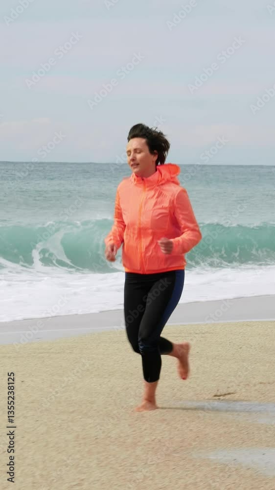 Chubby woman is jogging on beach against grey sky and stormy sea. Vertical video Chubby woman is jogging on beach against grey sky and stormy sea. Vertical video