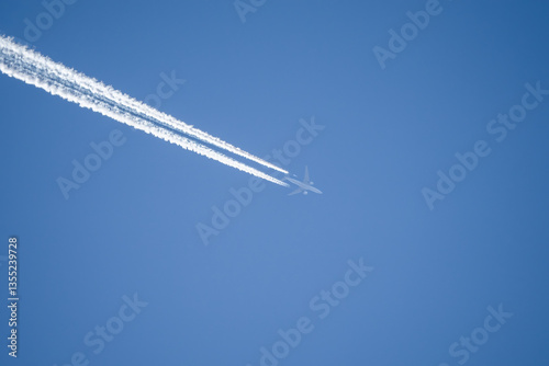 a twin engined jet liner aircraft in deep blue sky, contrails vapour trails