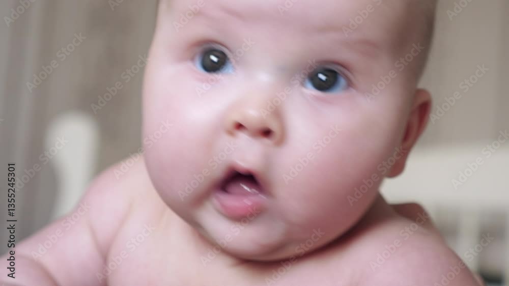 Adorable baby with wide open eyes drooling while lying at home exploring world Adorable baby with wide open eyes drooling while lying at home exploring world