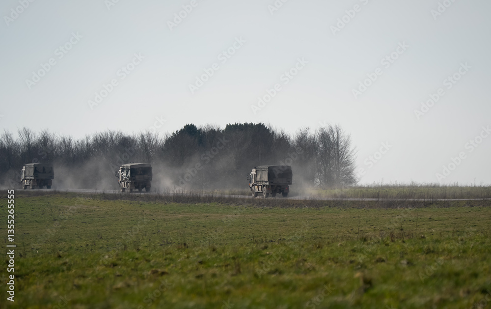 Fototapeta premium convoy of British army MAN SV HX 60 6x6 18.330 utility trucks moving along a dusty track