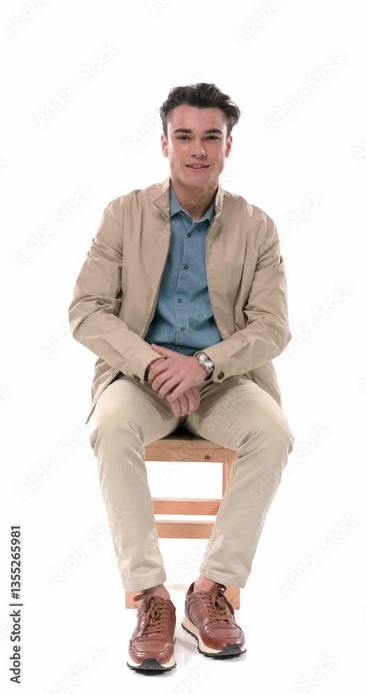 project video of happy young man adjusting sleeve, smiling and checking the time, fixing leg on chair, putting elbow on knee and thinking in front of white background project video of happy young man adjusting sleeve, smiling and checking the time, fixing leg on chair, putting elbow on knee and thinking in front of white background