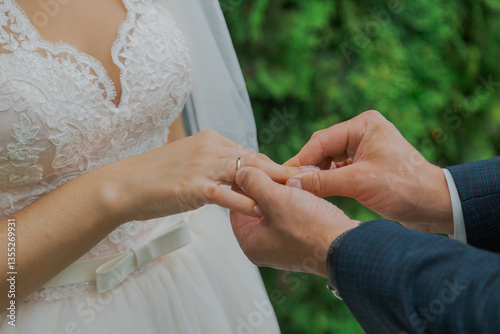 A handsome young groom puts on a ring to the bride on their wedding day, they are both happy. close-up