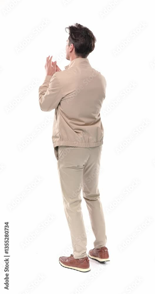 back view of young man applauding the victory, turning around and making thumbs up gesture and smiling on white background back view of young man applauding the victory, turning around and making thumbs up gesture and smiling on white background