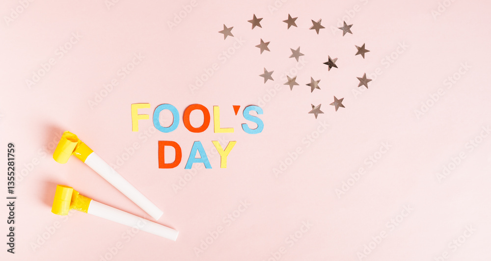 Happy April Fools' Day with colored letters, whistles and stars on pink web banner