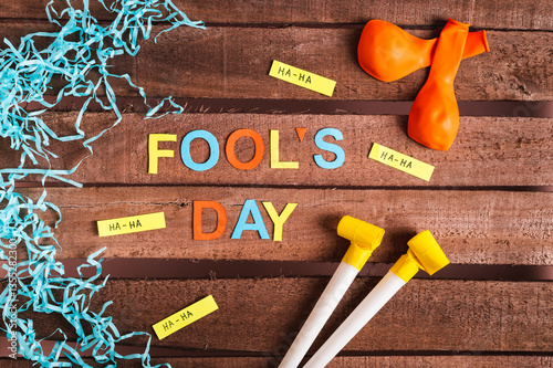 Obraz na płótnie April Fools' Day from colored letters, funny notes, whistles and balloons on a wooden background w salonie