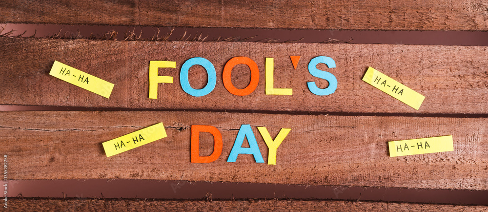 April Fools Day from colored letters, funny notes and paper on wooden top view web banner