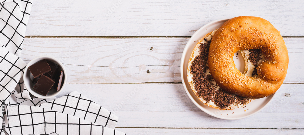 Sweet sandwich with butter, chocolate and sesame seeds on a plate on a table top view web banner