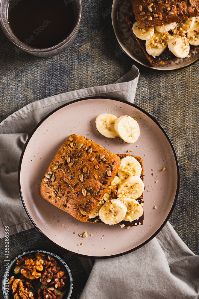Toast rye bread with chocolate and banana on a plate on the table top and vertical view