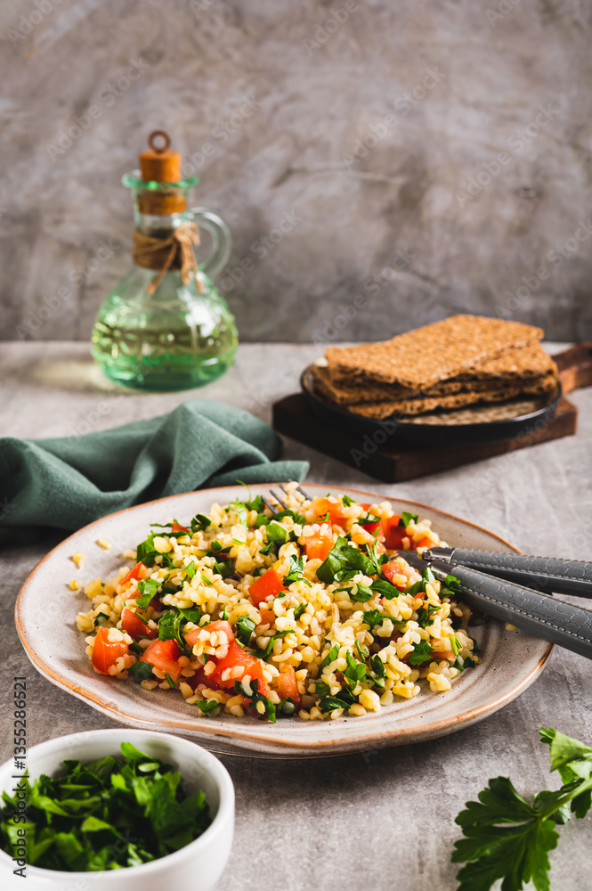 Tabbouleh salad with bulgur, tomato and parsley on a plate on the table vertical view