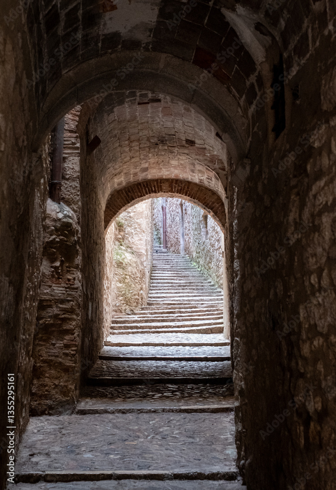 Fototapeta premium Narrow passage way with stone steps and arch, in the historic Jewish Quarter in the city of Girona in Catalonia, Spain. Jews lived and thrived in the city before the expulsion in 1492.