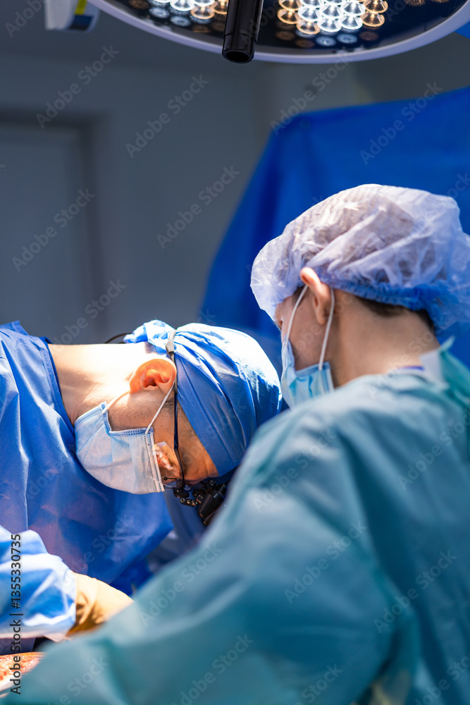 Fototapeta premium Surgeons at work in hospital. Surgeons in sterile attire focus intently during a complex procedure in a well-lit operating room.