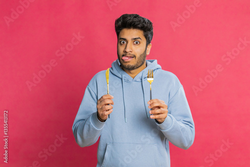 Quadro su tela Hungry Indian man holding fork and knife, eagerly anticipating a delicious meal, licking lips with excitement