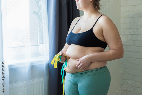 Foto Woman with fat belly, overweight female stomach, holding waist measurer