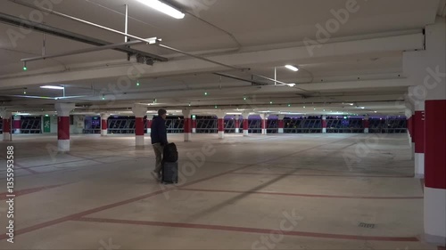Wallpaper Mural Stockholm, Sweden A man walks with a roller suitcase in a parking garage. Torontodigital.ca