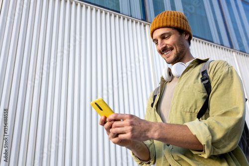 Smiling student using smartphone in front of modern building