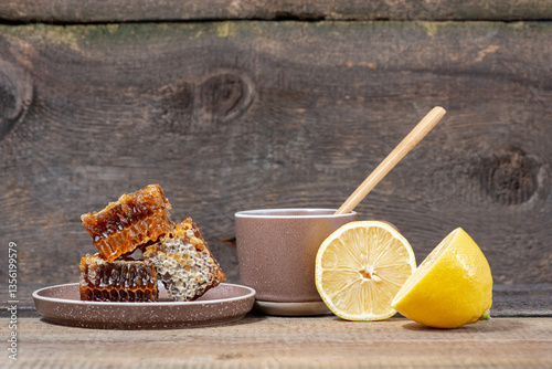Herbal tea in a ceramic mug, honey in a plate and lemon on a wooden table. Still life