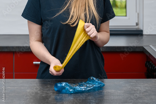Kobieta rozrywa żółte worki na śmieci I wyrzuca zużytą butelkę z plastiku po wodzie, segreguje smieci