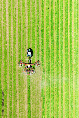Aerial view of a tractor working in a cultivated field during haymaking