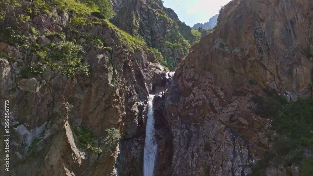 Small waterfall in mountain valley in mountains, close aerial drone view in sunny summer Kyrgyzstan. Clear weather and rugged terrain. Boom down camera movement, Small waterfall in mountain valley in mountains, close aerial drone view in sunny summer Kyrgyzstan. Clear weather and rugged terrain. Boom down camera movement,