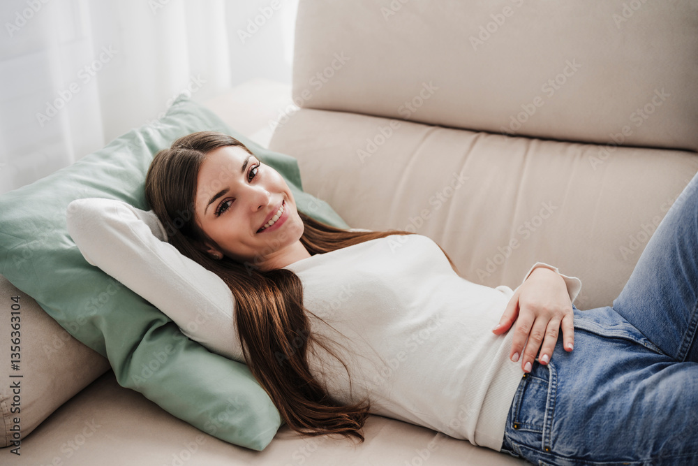 Woman relaxing on a sofa at home, smiling and looking content Woman relaxing on a sofa at home, smiling and looking content