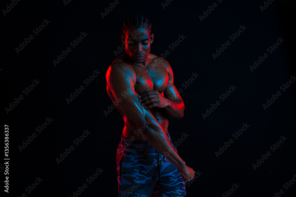 Athlete flexing muscles in colorful studio lighting Athlete flexing muscles in colorful studio lighting