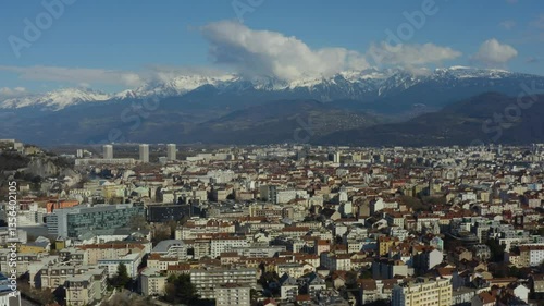 Aerial shot of the city of Grenoble surrounded by snow-capped mountains in winter, in France