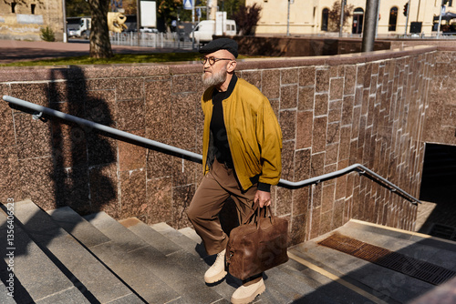 Bild auf Leinwand In a bustling cityscape, a stylish senior man ascends the stairs, combining fashion and elegance