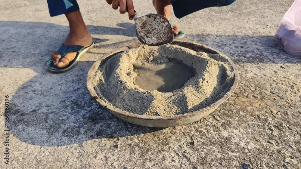 Construction Worker manually mixing cement, sand and water for work.