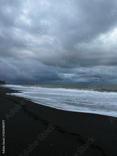 Obraz na płótnie Footprints on black sand beach under stormy clouds w salonie
