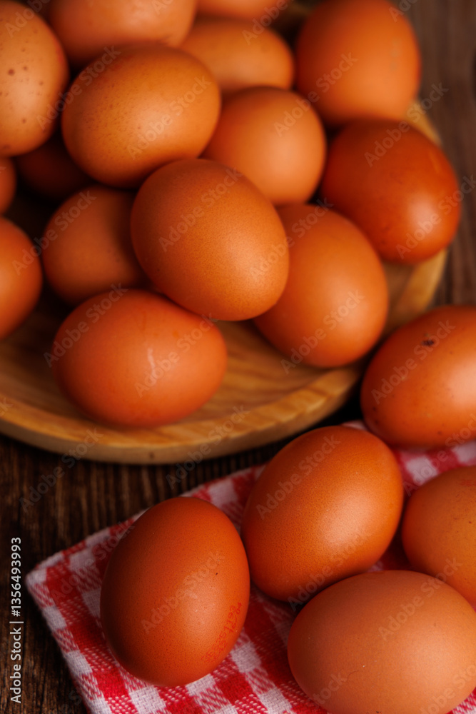 Rustic wooden plate with brown eggs placed over a red and white napkin on a wooden surface, highlighting economic inflation. Rustic wooden plate with brown eggs placed over a red and white napkin on a wooden surface, highlighting economic inflation.