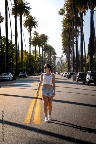 Young female tourist strolling down a Beverly Hills street with palm trees at sunset.
