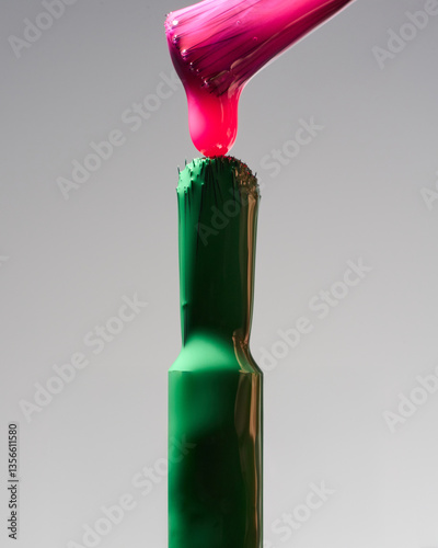 Bright green and pink nail polish flows down the brush, macro, creative background, color mixing    