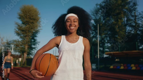 Teenage girl basketball player with ball over outdoor court background